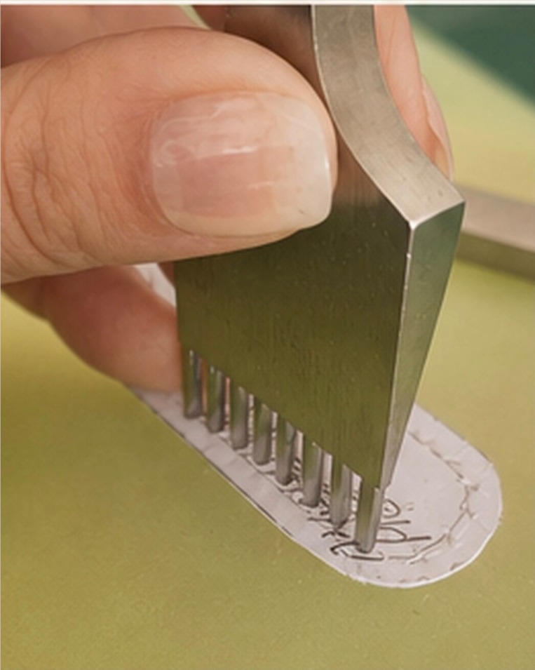 A hand marking stitch spacing with a pricking iron on a paper pattern at the workbench